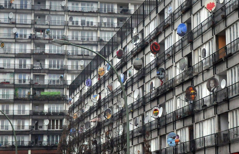 Hochhaussiedling mit vielen bunten Satellitenschüsseln auf den Balkonen.